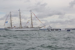 A sailboat sails alongside Energy Observer