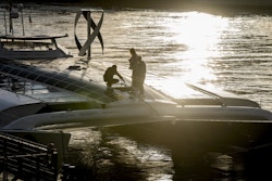 3 personnes sont sur le bras de liaison avant du bateau lors du coucher de soleil