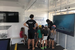 2 adultes et une dizaine d'enfants regardent un tableau de l'exposition