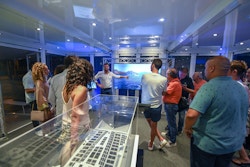 Victorien pointe du doigt l'image d'un écran devant plusieurs visiteurs de l'exposition