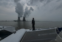 Un membre d'Energy Observer observe de la vapeur s'échappant d'une usine de pétrochimie